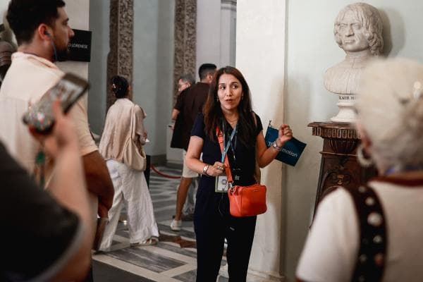 Tour guide speaking to a group of visitors inside the Uffizi Gallery.