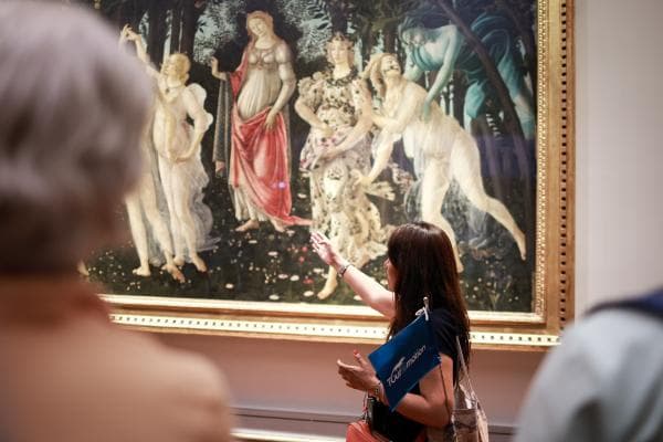 Expert guide describes Botticelli's Primavera to a group of visitors at the Uffizi Gallery.